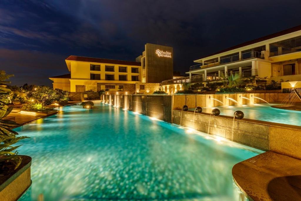 a swimming pool at night with a hotel at Nambiar Club Bellezea in Bangalore