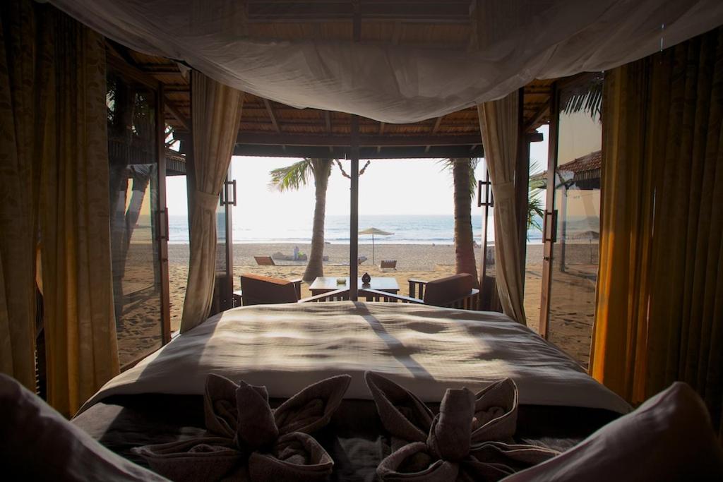 a bedroom with a bed with a view of the beach at Dunhill Beach Resort in Agonda