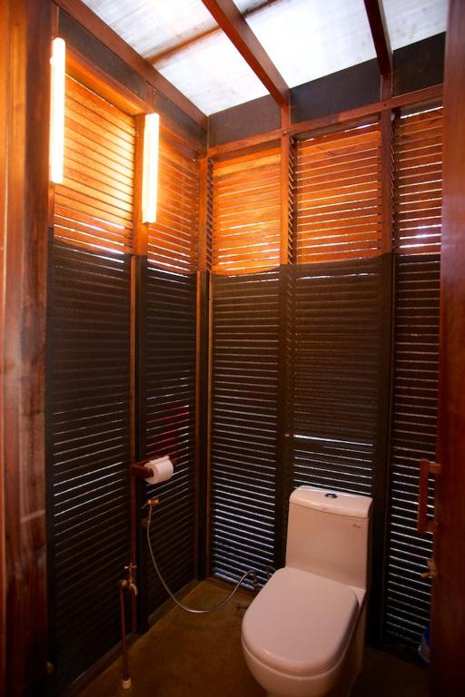 a bathroom with a toilet in a room with wooden walls at Dunhill Beach Resort in Agonda
