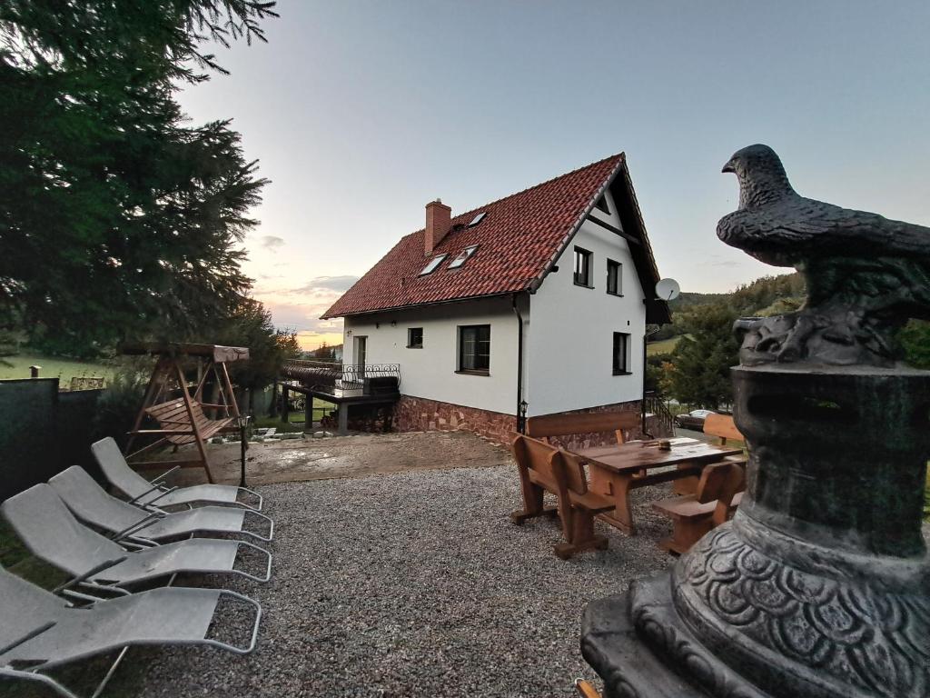 Dom nad Potokiem Sowa في Rzeczka: منزل به طاولة وكراسي وتمثال للطيور