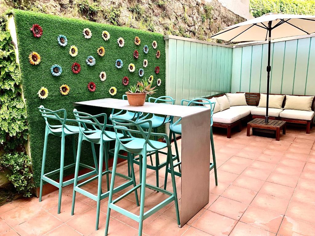 een patio met een tafel en stoelen en een muur met bloemen bij San Sebastián Fresh !! Vivienda & Terraza in San Sebastian