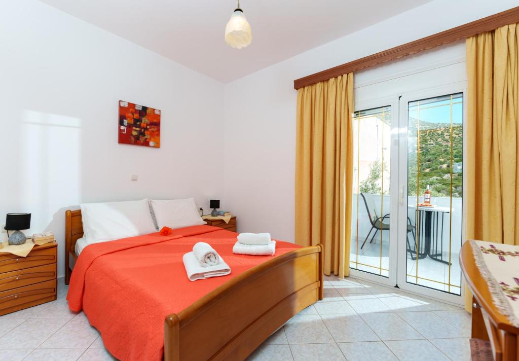 a bedroom with a bed with a red blanket and a balcony at Hara's Apartment 1 in Keratokampos