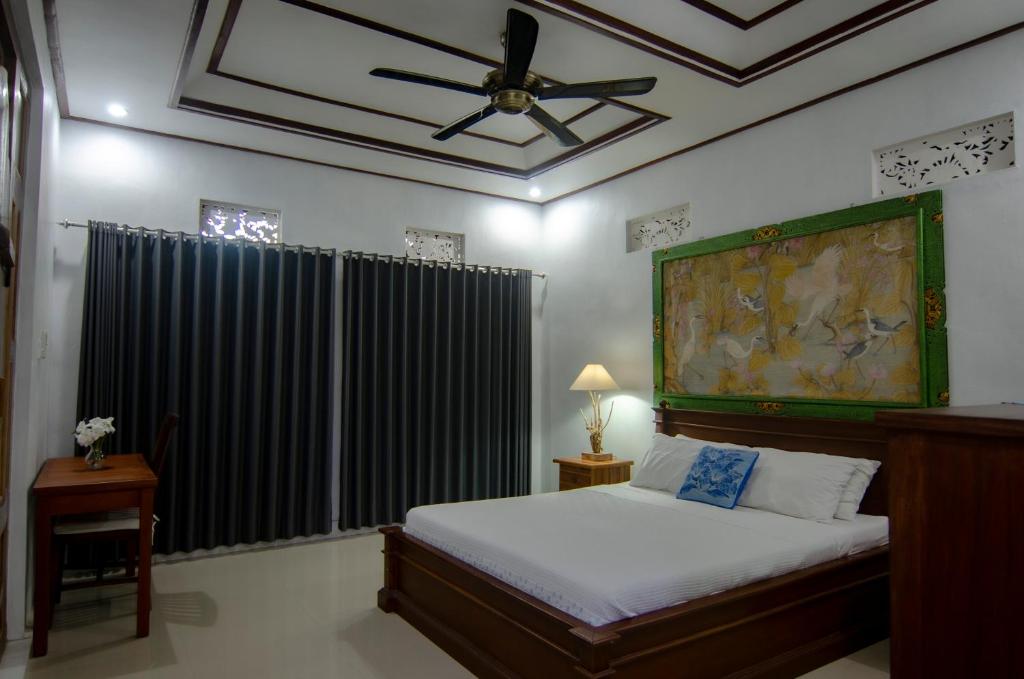 a bedroom with a bed and a ceiling fan at TRESNA HOMESTAY in Ubud
