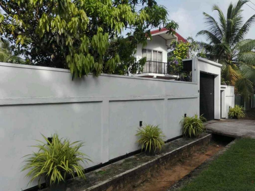 una casa blanca con una valla y algunas plantas en Dream Forest Rest en Ahangama