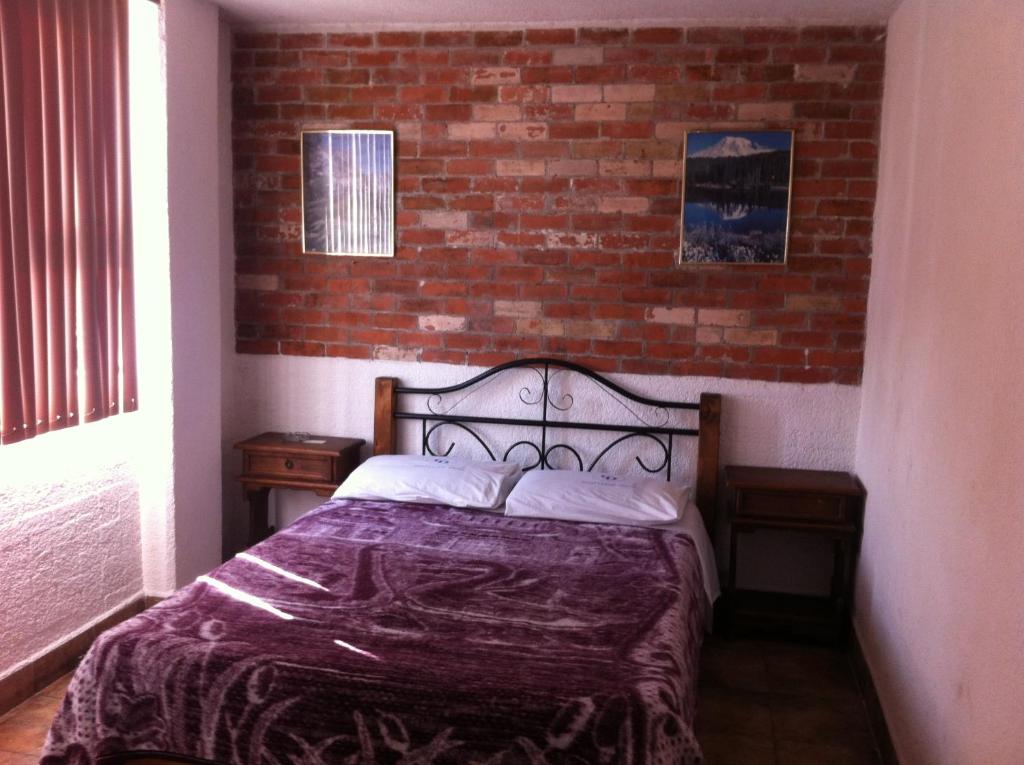 Bett in einem Zimmer mit Ziegelwand in der Unterkunft Hotel Centro Diana in Mexiko-Stadt