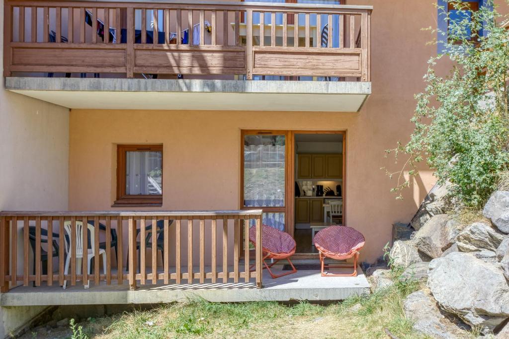 a home with a balcony and two chairs on a porch at Le Val 1800 - Appartement avec Terrasse in Valmeinier