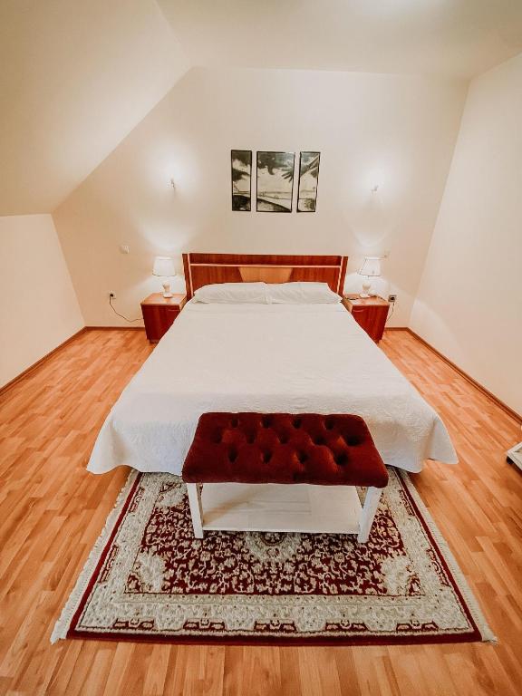 a bedroom with a large white bed with a red bench at Cosy bedroom for 2 with Balcony in a Family Villa in Turnu Măgurele