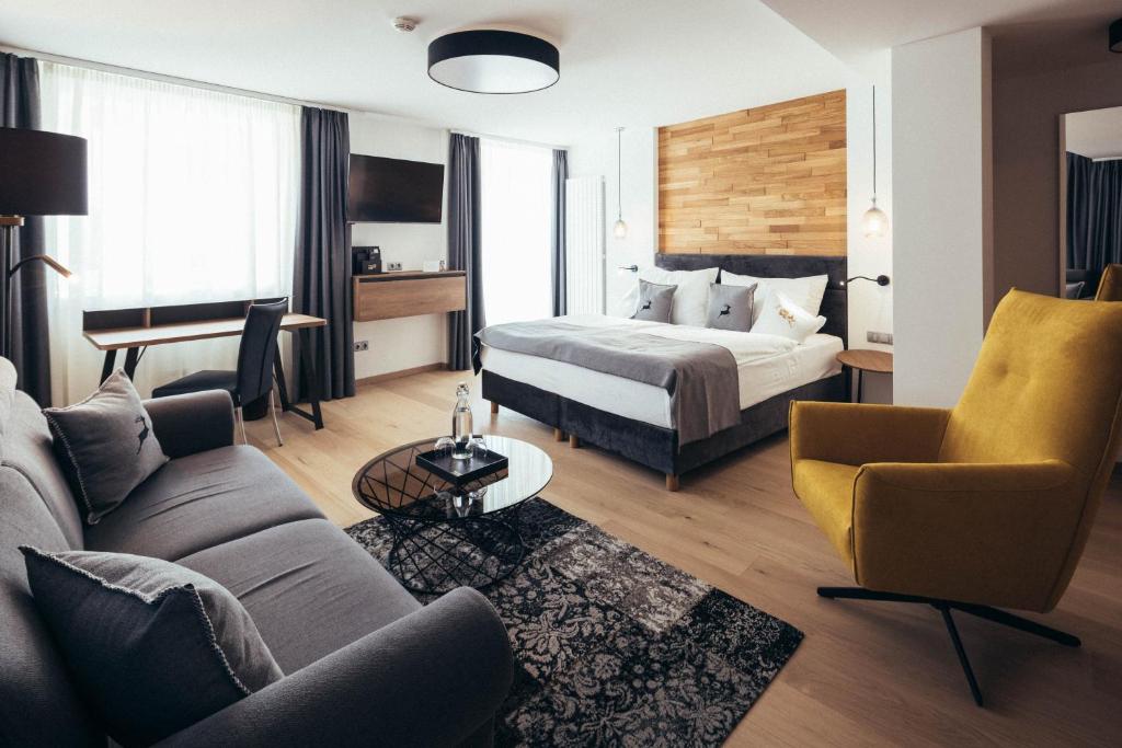 Habitación de hotel con cama y sofá en Genusshotel Goldene Rose en Silandro