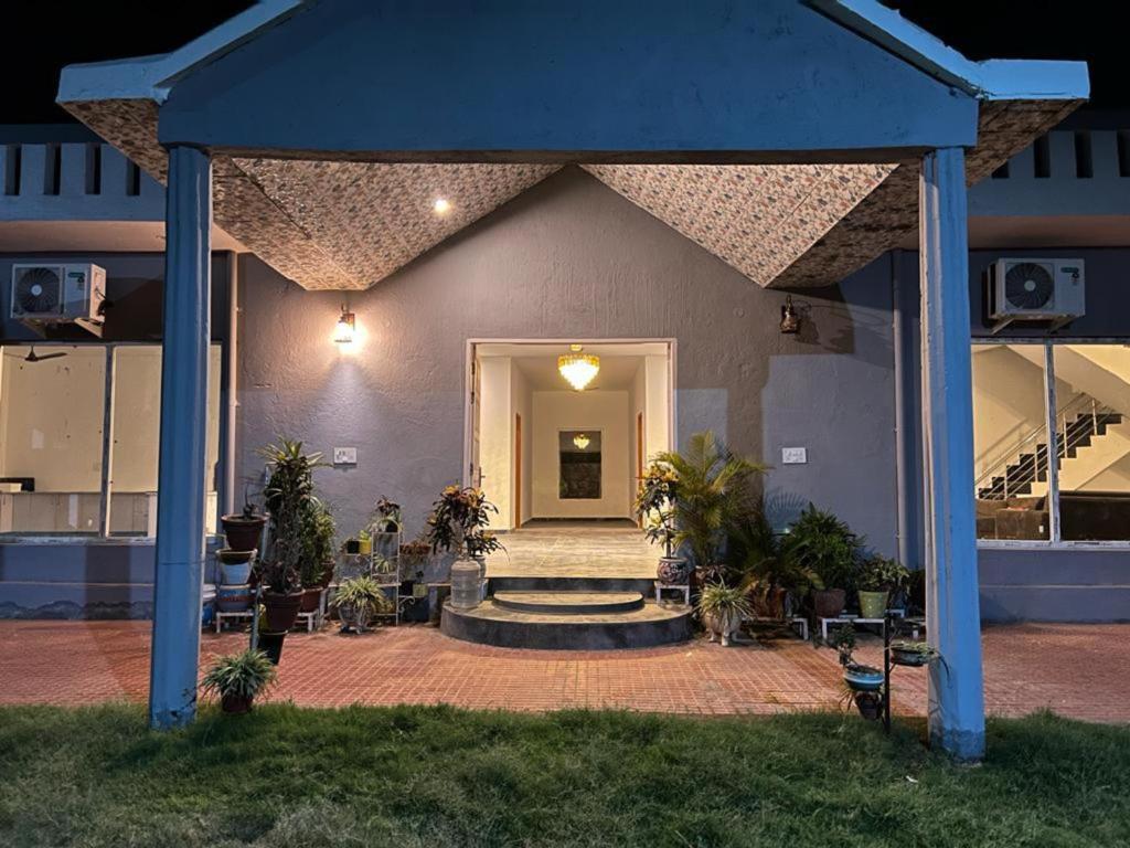 a house with a blue roof with a staircase leading to the door at Entrie 2 acre Farmhouse with Pool, 2 rooms & jacuzzi in both rooms in Gurgaon