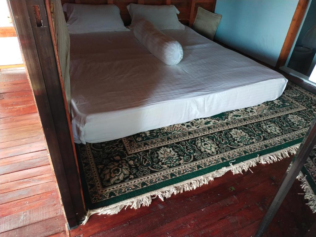 a bed in a room next to a rug at Homestay Pak Ucu 