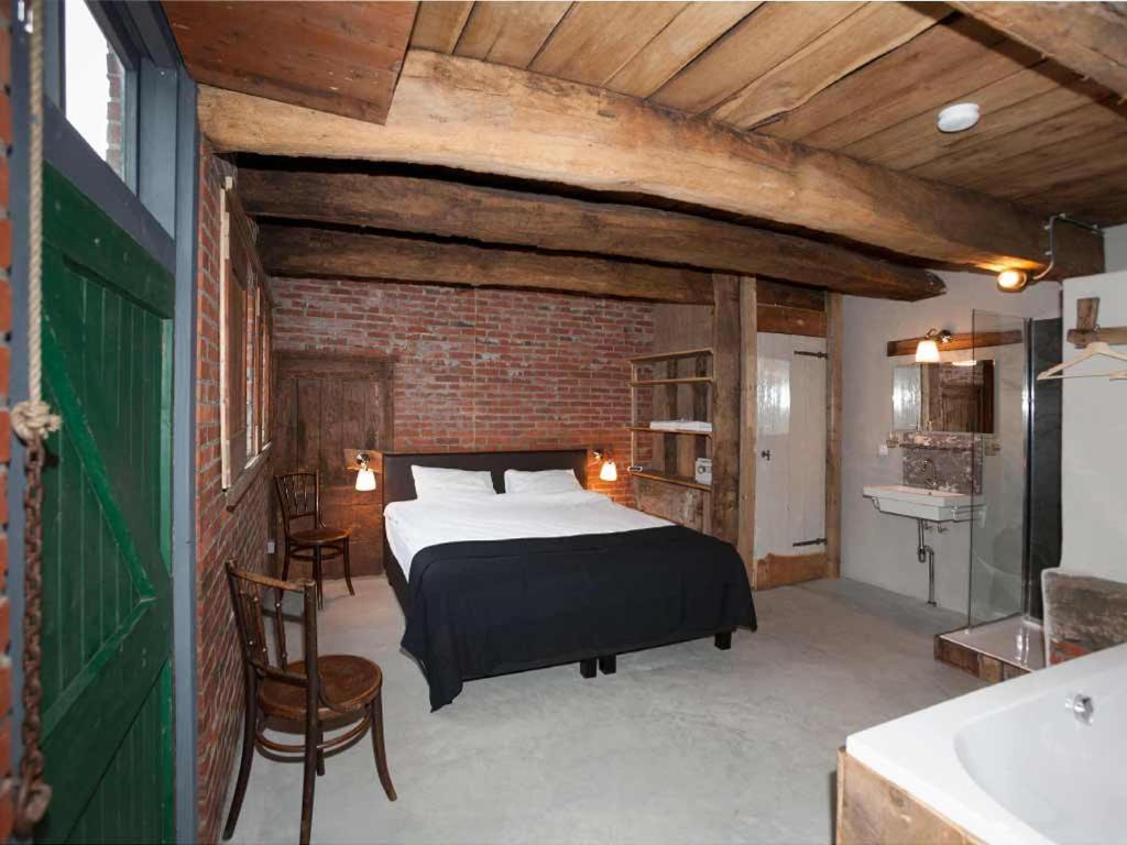 een slaapkamer met een bed en een bakstenen muur bij Norgerbrink in Norg