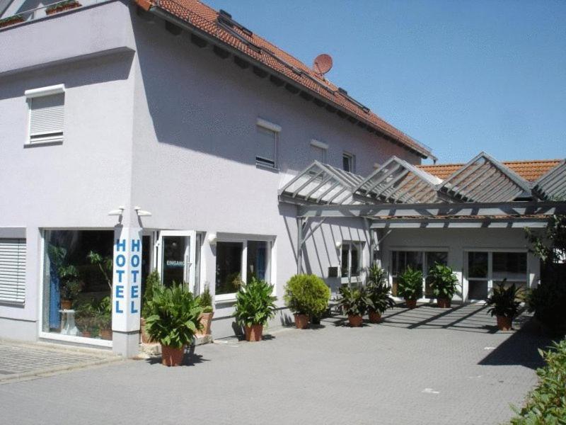 a white building with potted plants in front of it at Hotel Papillon in Lappersdorf