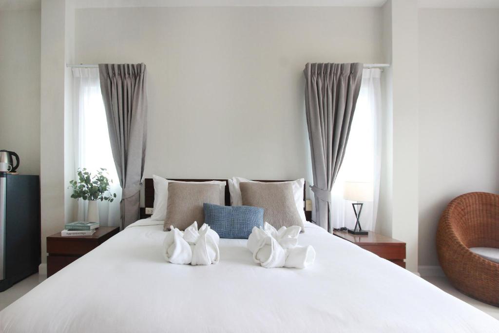 a white bed with four white shoes on it at The Langstan Suites in Nai Harn Beach