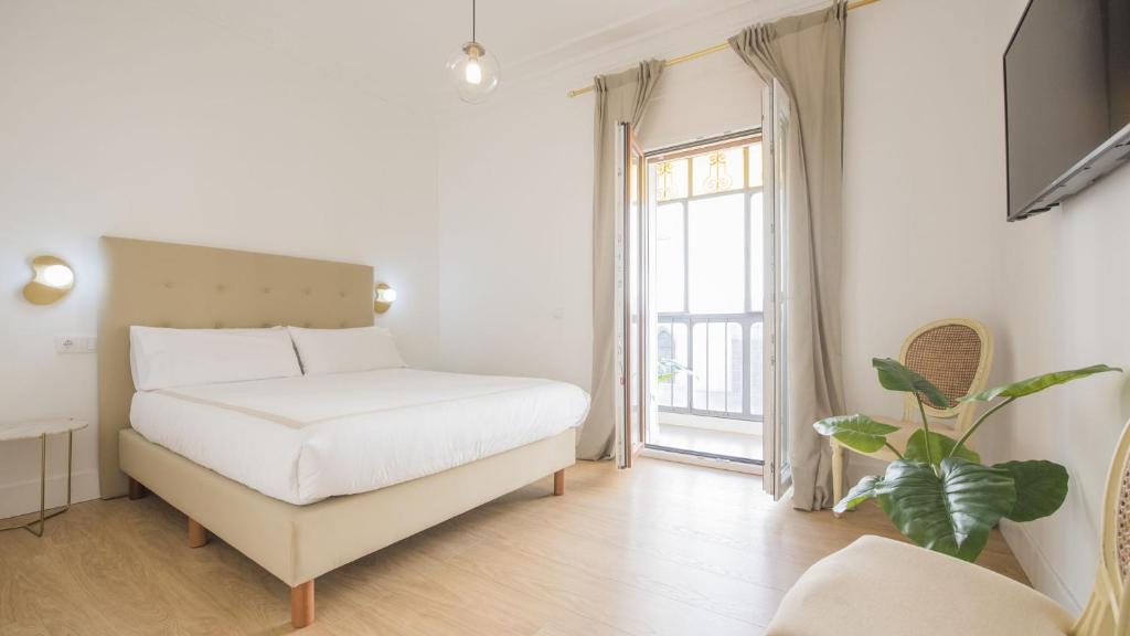 Habitación blanca con cama y ventana en Apartamentos Boutique Puerta de Reyes, en Toledo