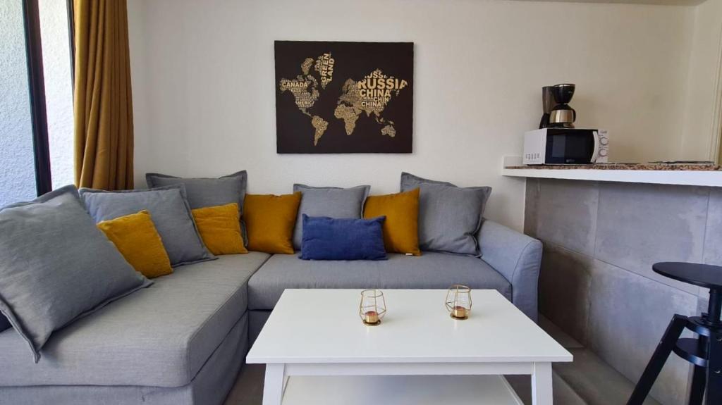 a living room with a grey couch with yellow and blue pillows at The SunSpot Apartment Playa del Inglés in Maspalomas