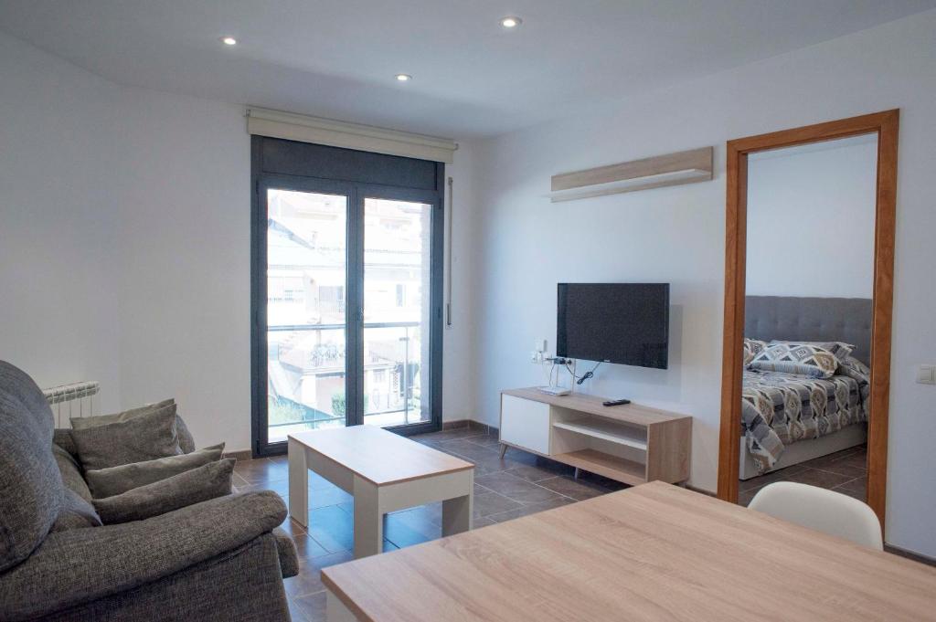 sala de estar con sofá, TV y cama en Apartament Bisaura de Ter, en Sant Quirze de Besora