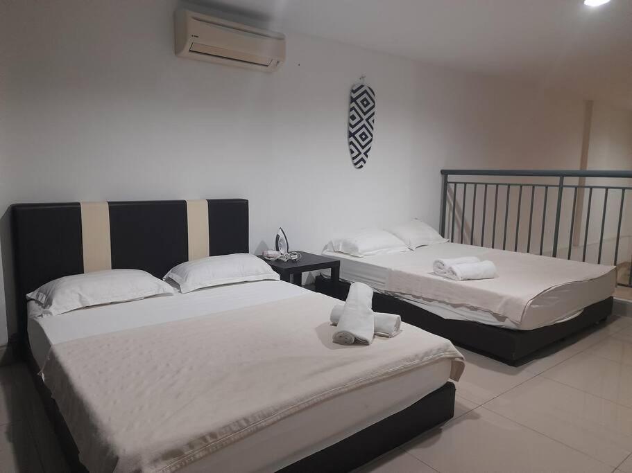 Dos camas en una habitación de hotel con toallas. en Double Storey PJ5 Soho Balcony Pool WIFI Netflix Field View, en Petaling Jaya