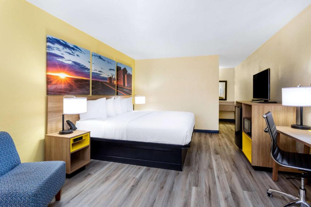 クローヴィスにあるDays Inn & Suites by Wyndham Clovisのベッドとデスクが備わるホテルルームです。