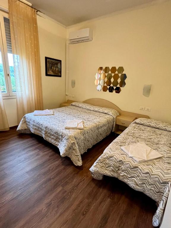 2 łóżka w pokoju z drewnianą podłogą w obiekcie Hotel degli Dei w mieście Pianoro