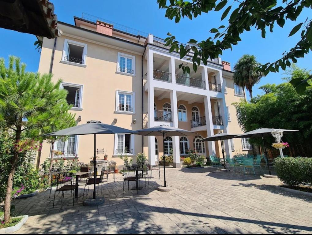 un edificio con mesas y sombrillas delante en Hotel TREVA, en Shkodër