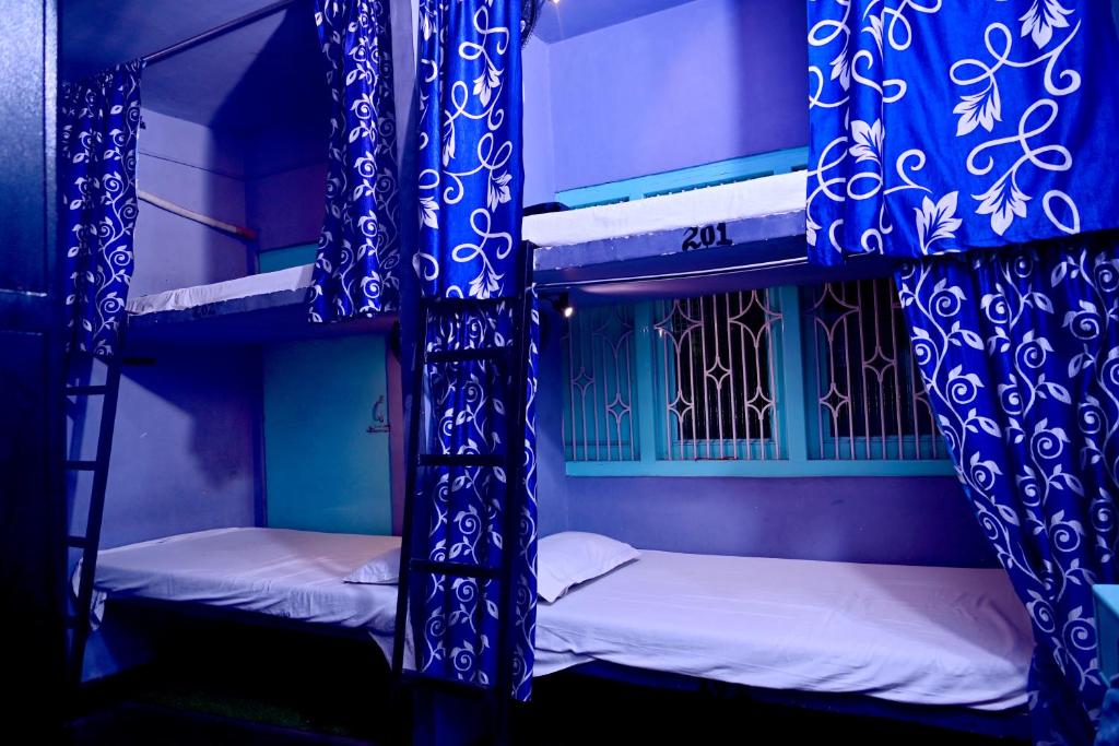 BANARAS REST HOUSE في فاراناسي: سريرين بطابقين مع ستائر زرقاء وبيضاء في الغرفة