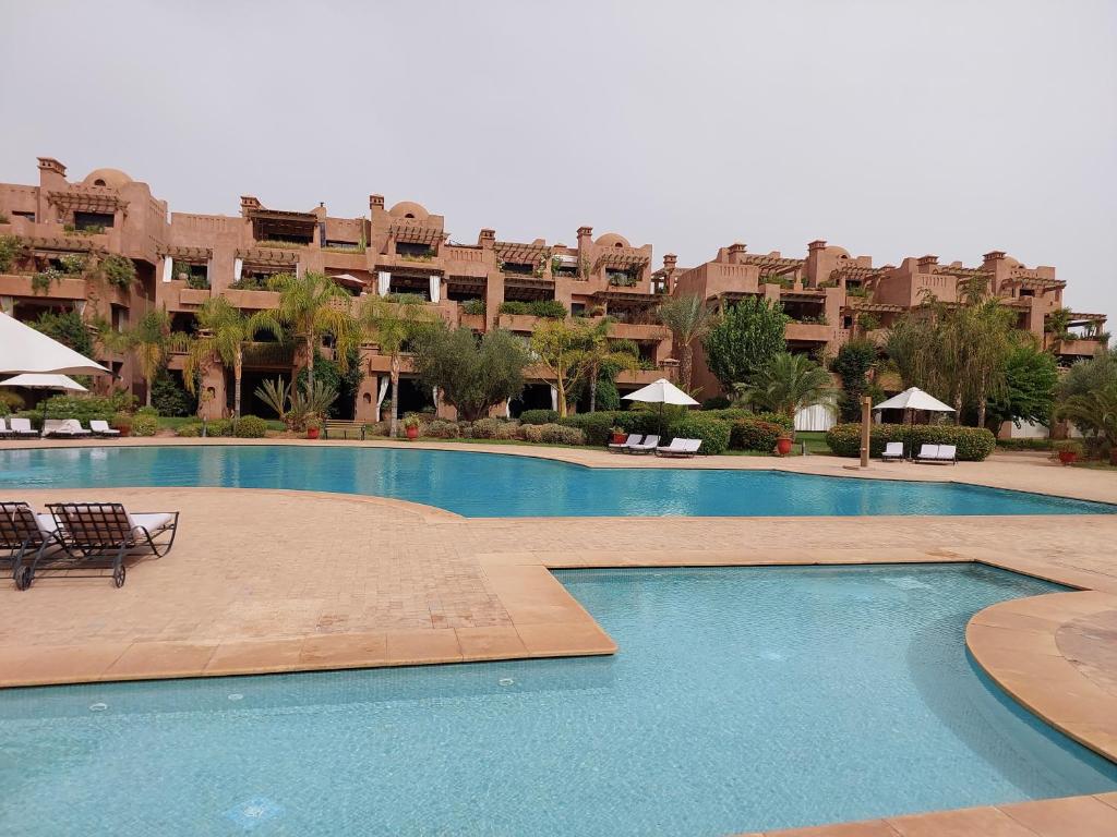 una gran piscina frente a un gran edificio de apartamentos en Appartement Marrakchia au jardin d'habgour, en Marrakech