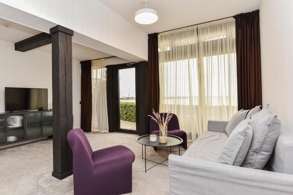 ein Wohnzimmer mit einem Sofa und lila Stühlen in der Unterkunft Apartamentai Ešerinėje in Neringa