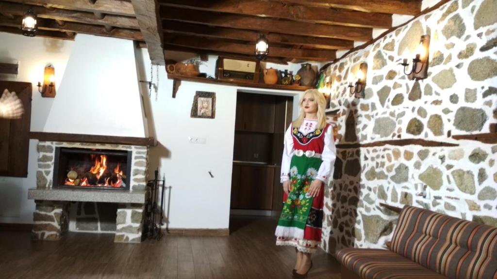 a young girl standing in a living room with a stone wall at Боримечковата къща in Kalofer