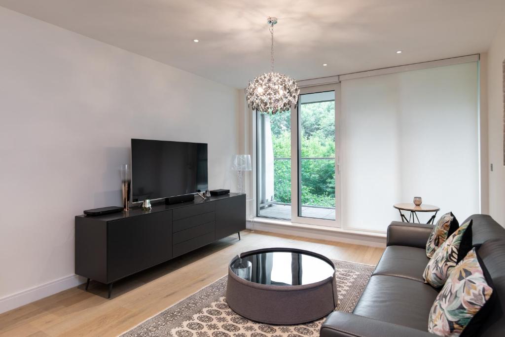 een woonkamer met een bank en een tv bij Chelsea Cascade London Flat in Londen