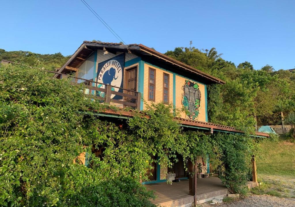 une maison entourée d'une terrasse couverte avec des vignes dans l'établissement Paraíso Hostel Praia do Rosa, à Praia do Rosa