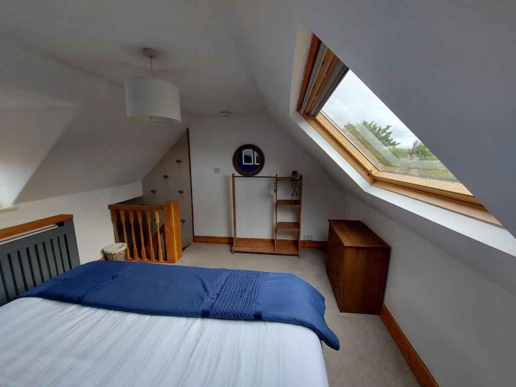 Schlafzimmer im Dachgeschoss mit einem Bett und einem Fenster in der Unterkunft Railway Cottage in Conwy