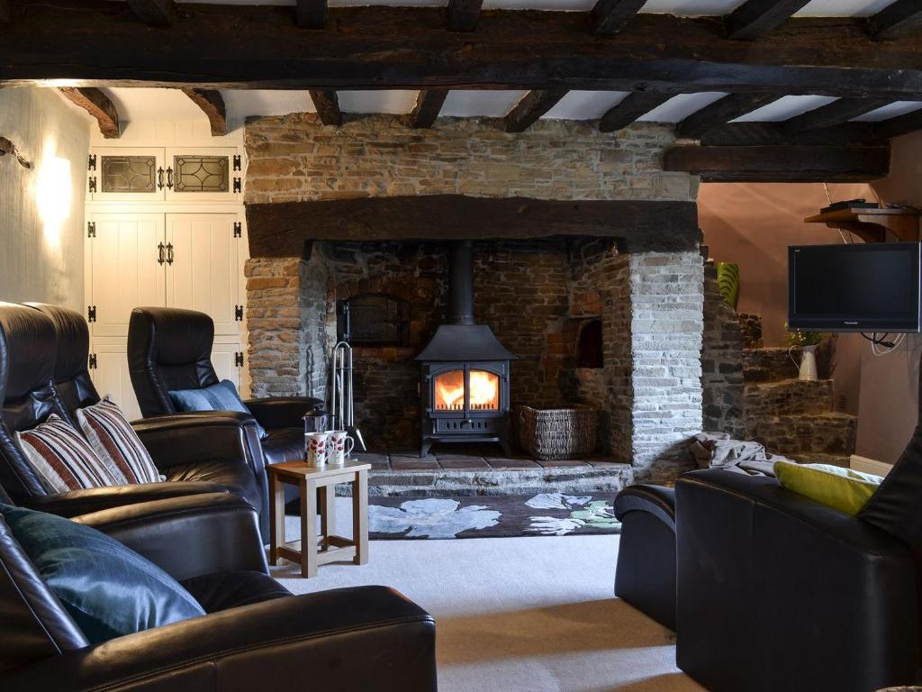 a living room with a stone fireplace with leather furniture at Isobels Cottage in Chapelton