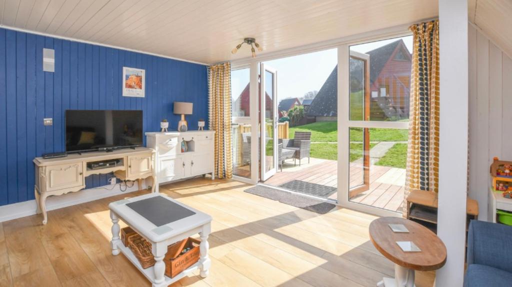 a living room with a tv and a large window at Foxes Sea Side Retreat Deluxe Chalet is a lovely holiday home tucked away on the Kent Coast in Kingsdown