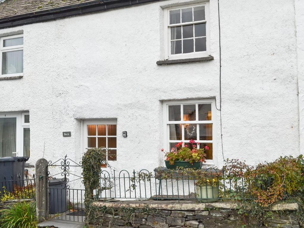 a white house with flowers in a window at Beck Cottage in Ambleside