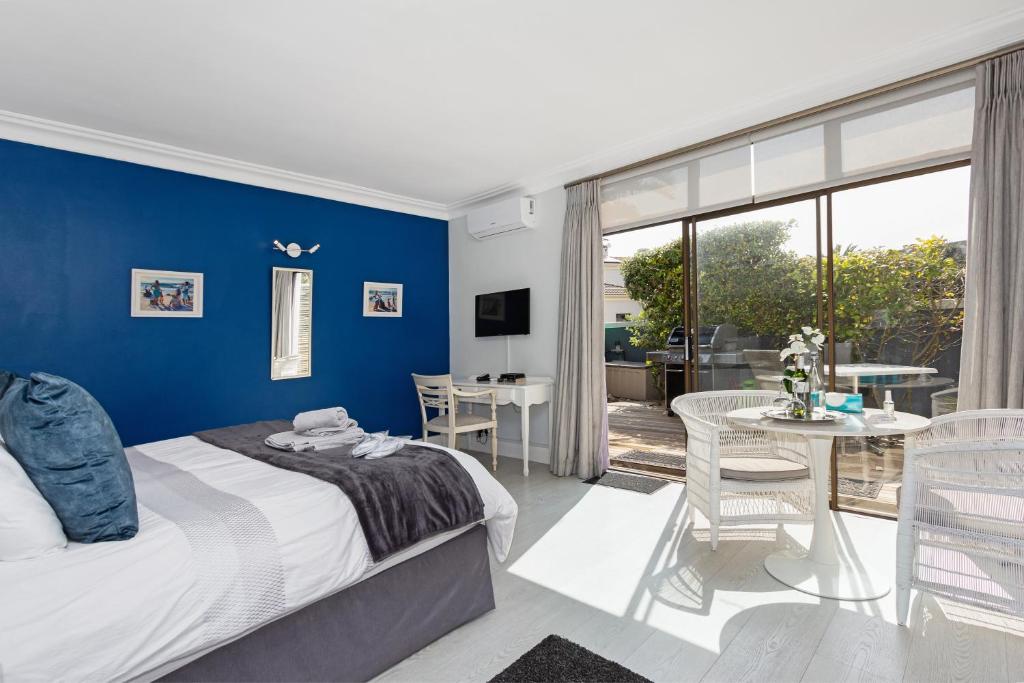 una camera da letto con pareti blu, un letto e un tavolo di OCEAN BREEZE SUNSET BEACH - Cape Town a Città del Capo