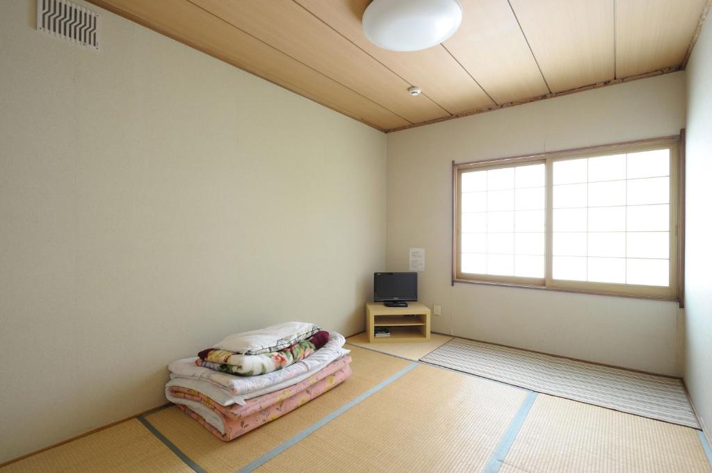 an empty room with a bed and a television at Sapporo Inn Nada in Sapporo