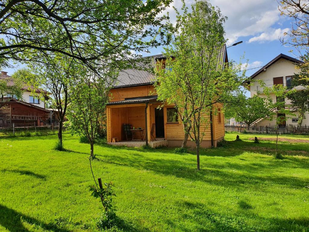 帕萊的住宿－Pan Koran Vikendica Pale, Jahorina，绿色草地和树木的院子内的房子