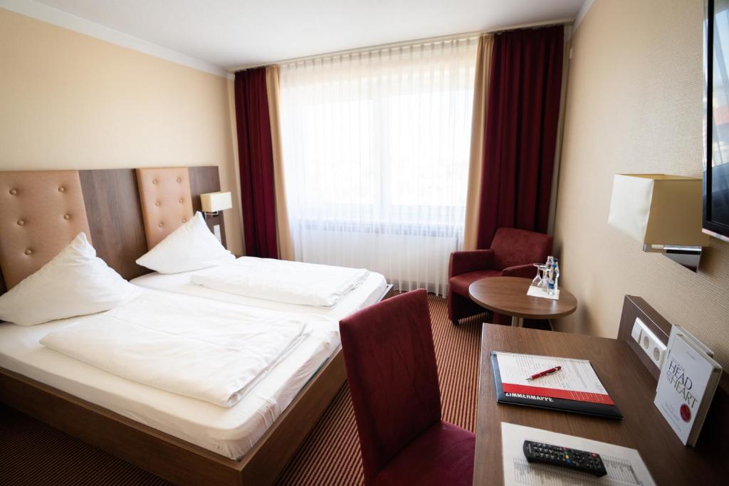 a hotel room with a bed and a chair and a table at Europa Kehl Hotel in Kehl am Rhein
