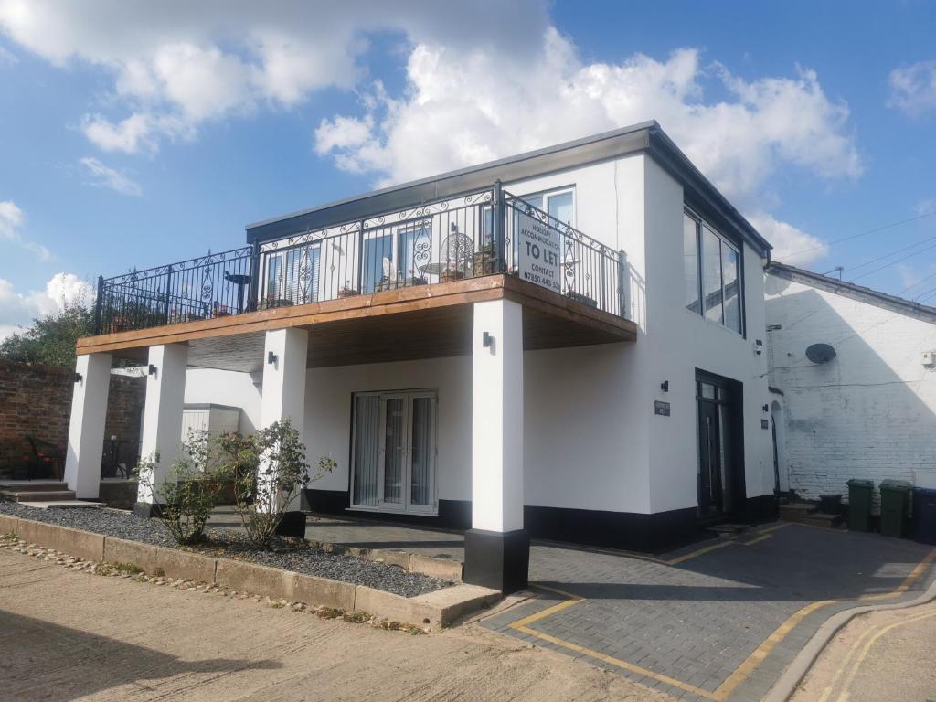 a white house with a balcony on top of it at Tallets Apartment with Balcony & Parking in Tewkesbury