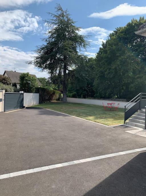 un parking avec un arbre et une clôture dans l'établissement La maison de la vallée, à Ranville