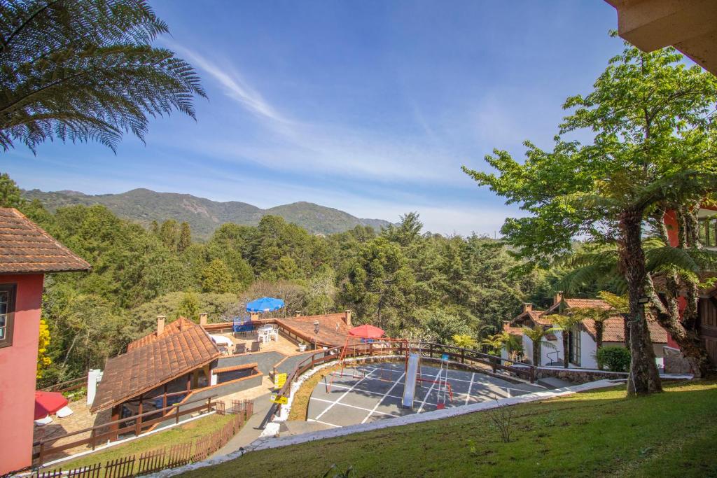 un complejo con piscina y montañas de fondo en VELINN Hotel Ninho do Falcão en Monte Verde