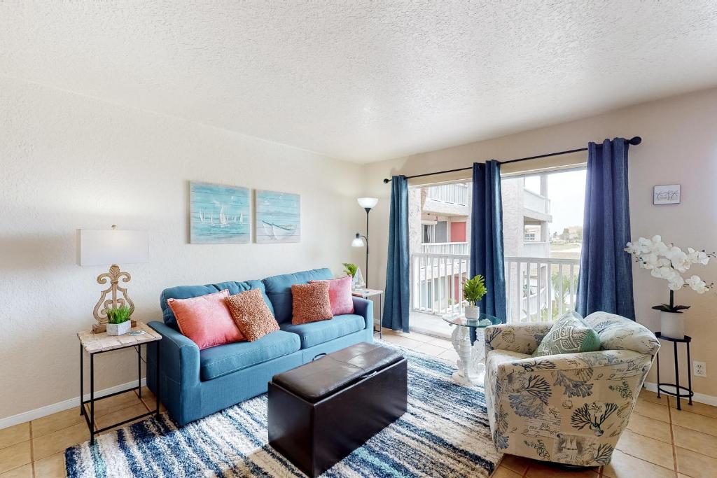 a living room with a blue couch and a chair at Mystic Harbor 207 in Padre Island