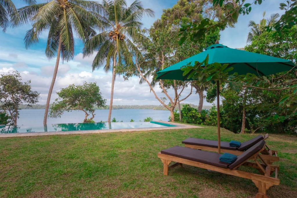 a bench with an umbrella next to a pool at Serendipity Lake - Hikkaduwa in Hikkaduwa