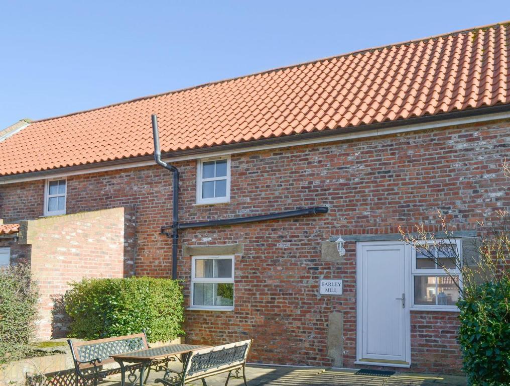 a brick building with two benches and a white door at Barley Mill - Uk11148 in Eshott