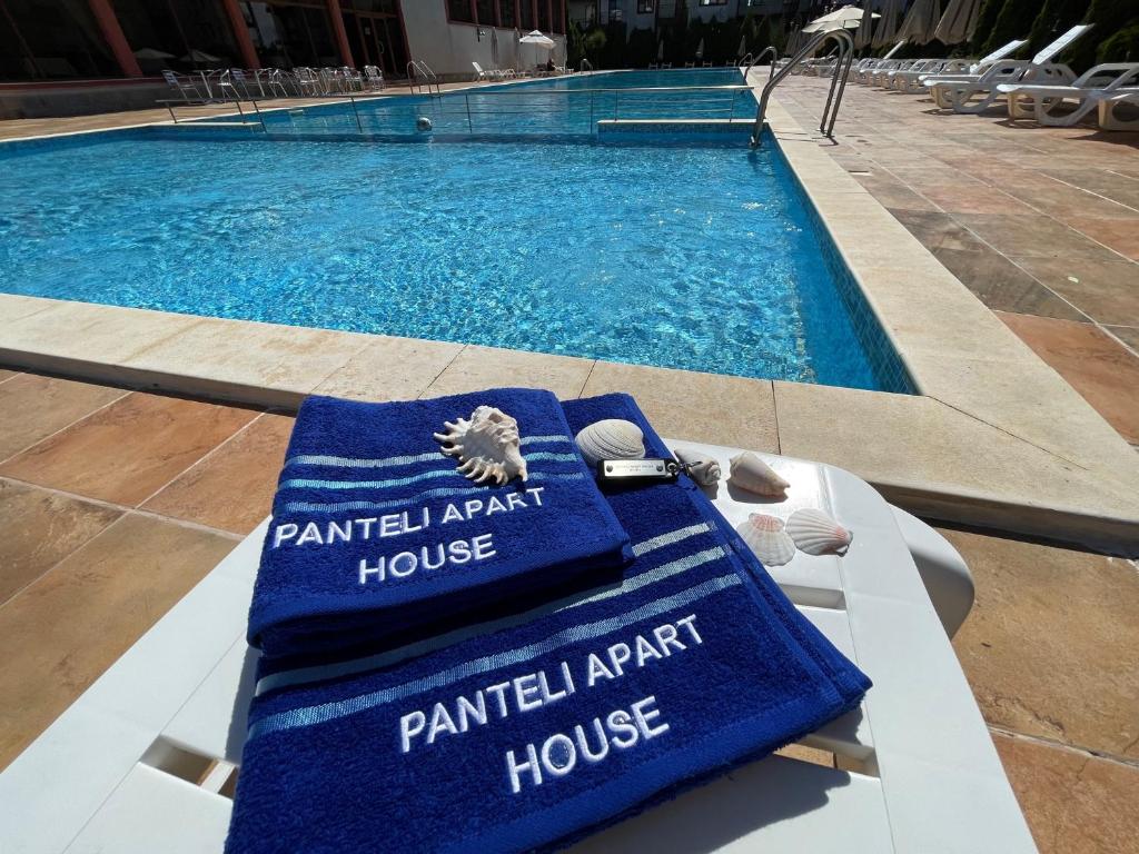 a swimming pool with a pair of towels on a bench at PANTELI APART HOUSE in Aheloy