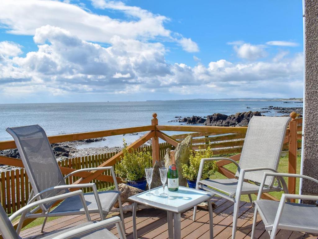 a patio with chairs and a table with a view of the ocean at Seashore Retreat in Johnshaven