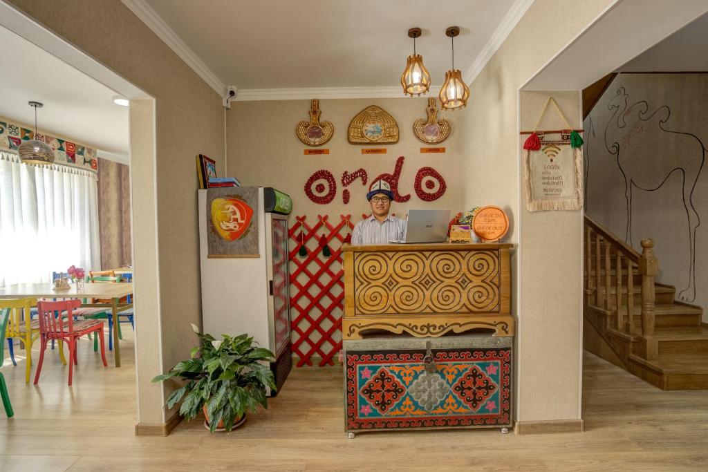 a man is standing behind a counter in a restaurant at Ordo Hotel in Karakol