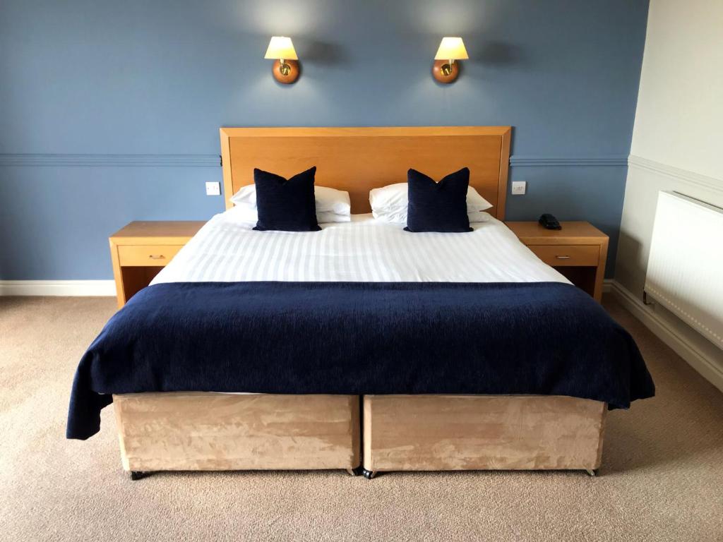 a bedroom with a large bed with blue walls at Dalmeny Hotel in Lytham St Annes