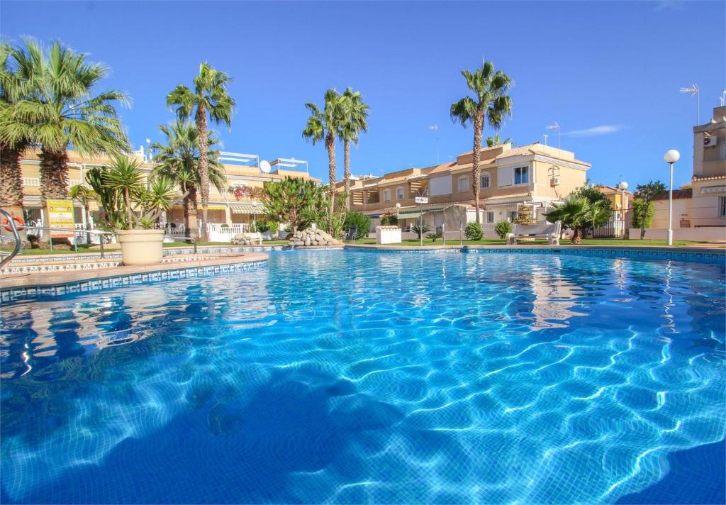 a large swimming pool with palm trees and buildings at Poolside 2 Bedroom 2 Bathroom Apt, Ultra Fast Wi-Fi & Terrace in Los Alcázares
