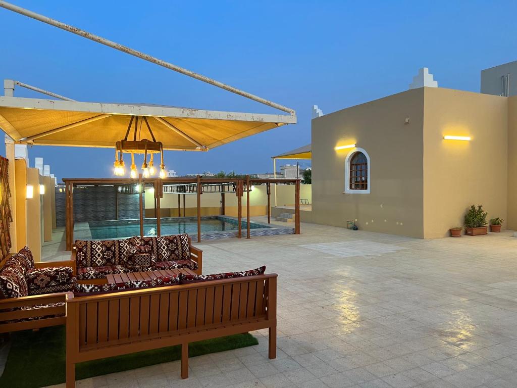 eine Terrasse mit einer Bank und einem großen Sonnenschirm in der Unterkunft Al Shiya Chalet in Sur